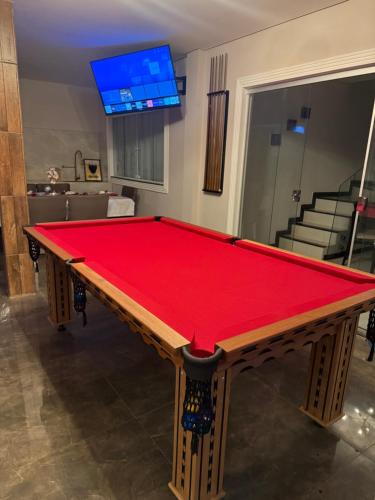 a pool table in a room with a red cloth at Luxuosa Casa, 10 Min do Minas Shopping and Hospitals in Belo Horizonte