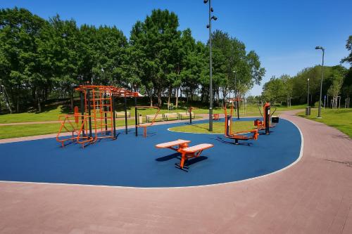 a park with a playground with slides and benches at JM Apartment in Plungė