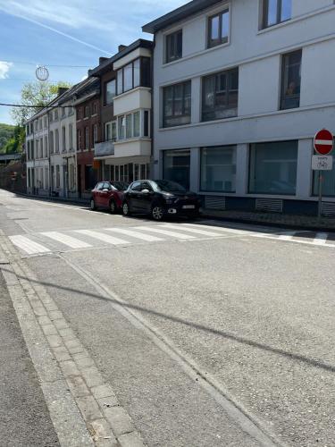 an empty street with cars parked in front of buildings at Résidence d'Angelo in Huy