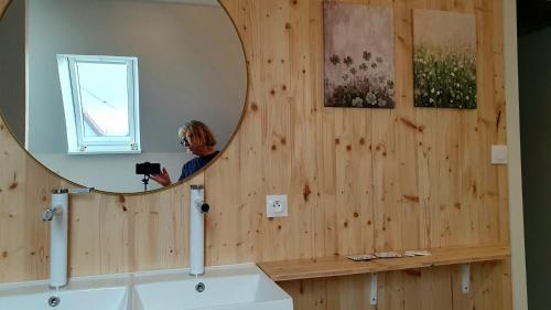 une femme prenant une photo d'un miroir dans une salle de bains dans l'établissement Le petit FrEd, à Seebach