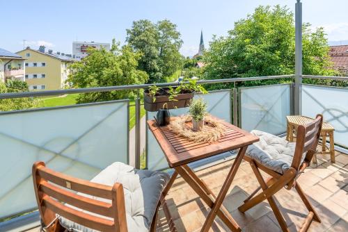 a balcony with a wooden table and two chairs at OG2 R 3-Zimmer City Wohnung 15min bis Salzburg in Freilassing