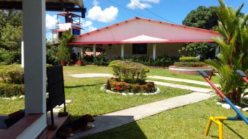 a house with a dog laying in the grass at HOTEL EL VAQUIANO o FINCA ALTAMIRA in Estación El Salto