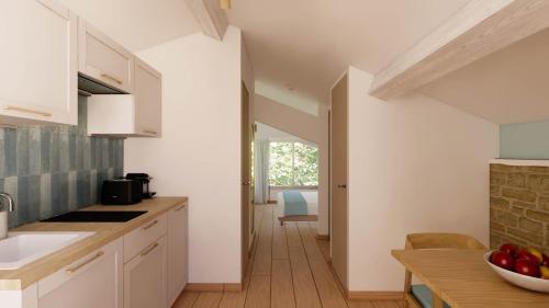 サン・シル・シュル・メールにあるVilla Onyra - Reflet d'Alizea - Appartement à 100m de la merのキッチン(白いキャビネット、フルーツボウル付きのテーブル付)