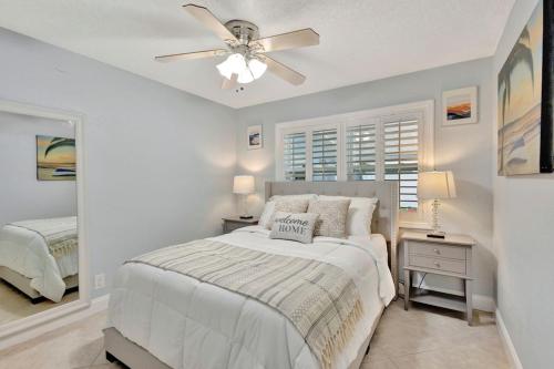 a white bedroom with a bed and a ceiling fan at Barefoot In Lantana in Lantana