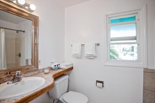 a bathroom with a toilet, sink and tub at Ocean Lodge Santa Monica Beach Hotel in Los Angeles