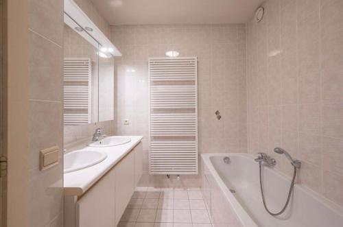 a bathroom with two sinks and a tub and a shower at Appartement aan zee Blankenberge in Blankenberge