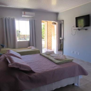 a bedroom with a purple bed with a tv on the wall at Pousada Floradas da Serra in Chapada dos Guimarães