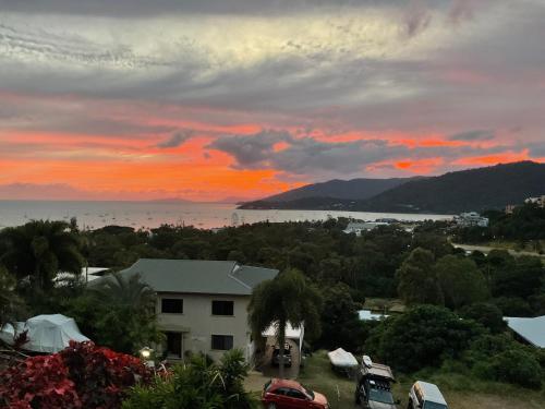 a sunset over a house with cars parked in a yard at Bella Vista Pets ok no pet without Calling host prior to booking t&C apply in Airlie Beach