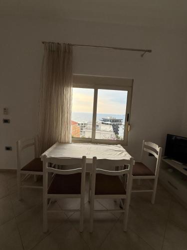 un tavolo e sedie in una stanza con una finestra di Nick's Apartment a Sarandë