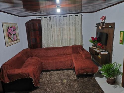 a living room with a large couch and a television at Casa Florânia, Campos do Jordão in Campos do Jordão