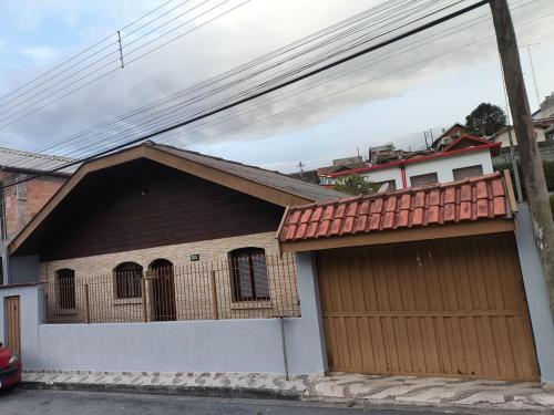 a house with a garage with a red roof at Casa Florânia, Campos do Jordão in Campos do Jordão