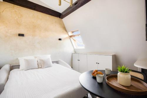 une chambre avec un lit blanc et une table dans l'établissement Luxury Studio Parc Monceau, à Paris