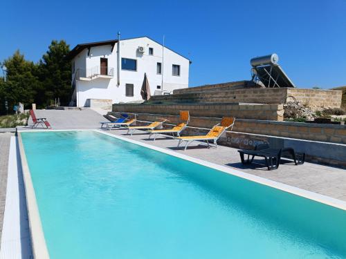 a swimming pool with chairs and a house in the background at CASA RURALE IMPASTATO in Montevago