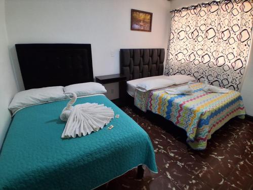 a bedroom with two beds with a green blanket at Hostal las vegas Malaga in Estación El Salto
