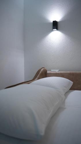 a light above a bed with a white pillow at Apartments Kayaville in Sjenica