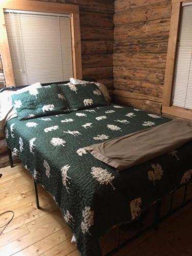 a bedroom with a bed with a green blanket at Cascade Log Cabin | Mt Rainier, WIFI, Log Cabin in Packwood