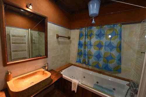 a bathroom with a tub and a sink and a mirror at Casal da Serra in Penha Garcia