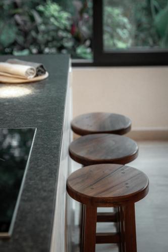 a row of wooden stools at a counter at Ka'ana Condo in Tulum