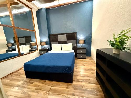 a bedroom with a bed with a blue comforter at RMS Hostal - Condesa in Mexico City