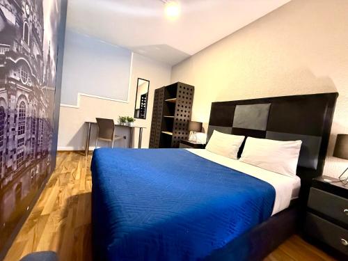 a bedroom with a bed with a blue blanket at RMS Hostal - Condesa in Mexico City