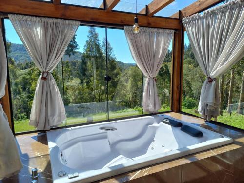a large bath tub in a room with windows at Chalés Sol da Serra - Eucalipto in Rio Rufino