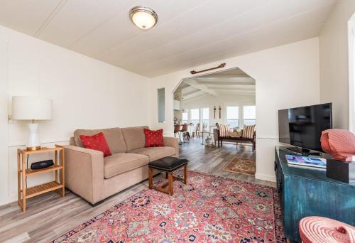 a living room with a couch and a flat screen tv at The Pink House - Dungeness Waterfront Home in Sequim