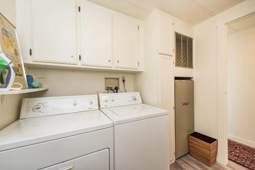 a kitchen with white cabinets and a washer and dryer at The Pink House - Dungeness Waterfront Home in Sequim
