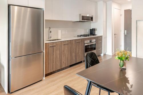 a kitchen with a stainless steel refrigerator and a table at Scenic 2BR RiverView Suite in Downtown in Calgary