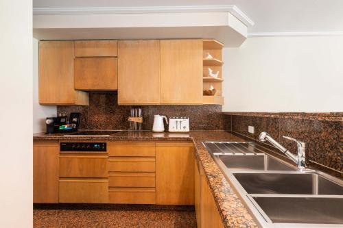 Una cocina con gabinetes de madera y un fregadero. en Mirage Resort Villa 128 with access to Sheraton Facilities, en Port Douglas
