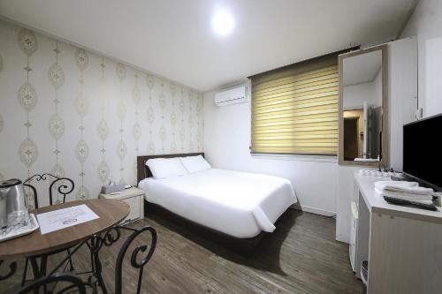 済州市にあるHotel CLのベッドルーム(白いベッド1台、デスク、シンク付)