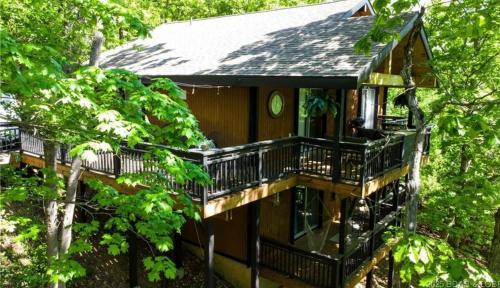 a tree house with a deck in the woods at Margarita Dreams in Osage Beach