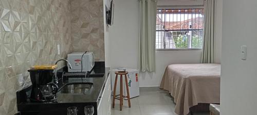 een keuken met een koffiezetapparaat op een aanrecht naast een bed bij Aeroporto e praia loft casal in Vitória