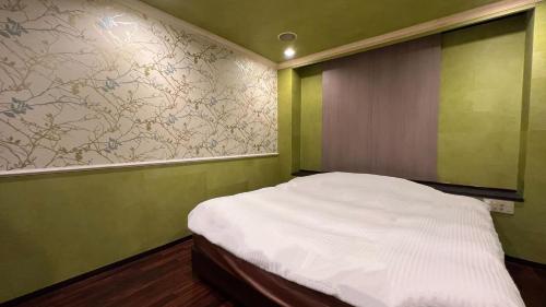 a small room with a bed with green walls at ホテルリンクス in Kashiwa