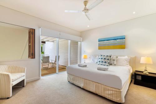 Un dormitorio con una cama grande y una silla. en Mirage Resort Villa 142 with access to Sheraton Facilities, en Port Douglas