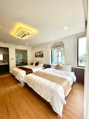 two beds in a large room with wood floors at Time Villa in Tam Ðảo