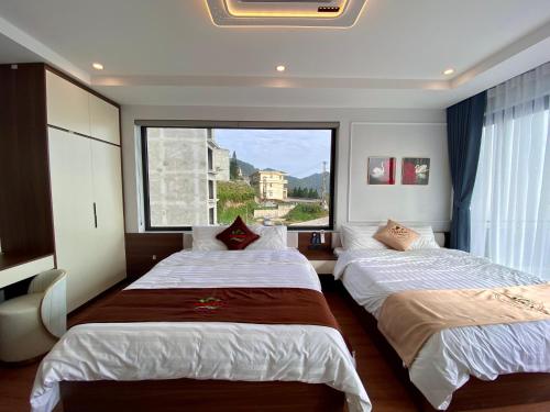two beds in a room with a large window at Time Villa in Tam Ðảo