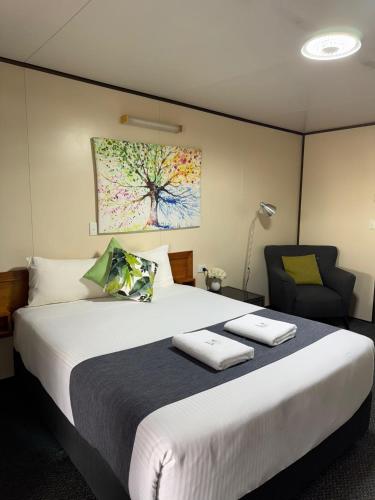a bedroom with a large bed and a chair at Cattle Camp Motel in Taroom