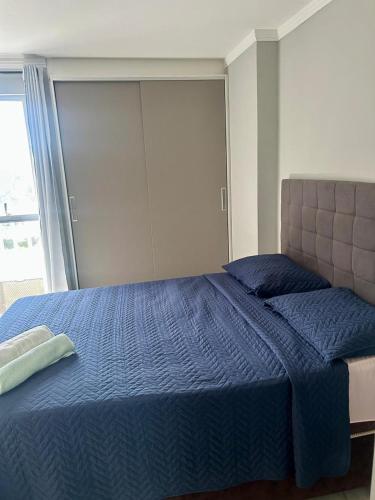 a bedroom with a blue bed with a large window at Catolé Comfort Flat in Campina Grande