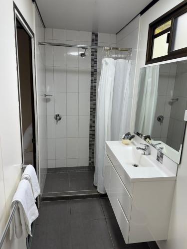 a white bathroom with a sink and a shower at Cattle Camp Motel in Taroom