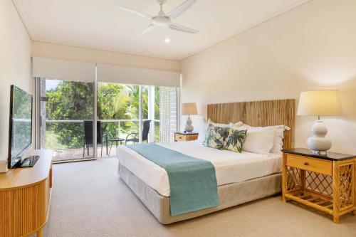 Un dormitorio con una cama y una ventana grande. en Mirage Resort Villa 155 with access to Sheraton Facilities, en Port Douglas