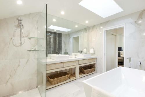 Un baño blanco con lavabo y ducha. en Mirage Resort Villa 156 with access to Sheraton Facilities, en Port Douglas