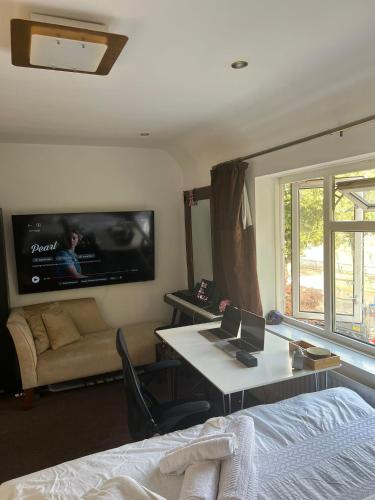 a bedroom with a bed and a tv on the wall at The Olive Tree Keys in Dagenham