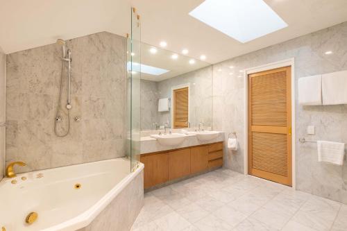 a bathroom with a tub and a sink and a shower at Mirage Resort Villa 157 with access to Sheraton Facilities in Port Douglas