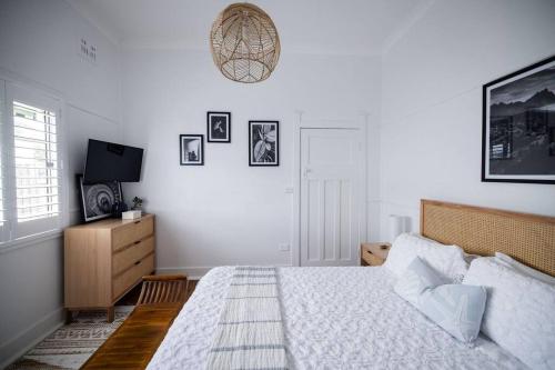 a white bedroom with a bed and a tv at Sea Cliff Sands Gerroa in Gerroa