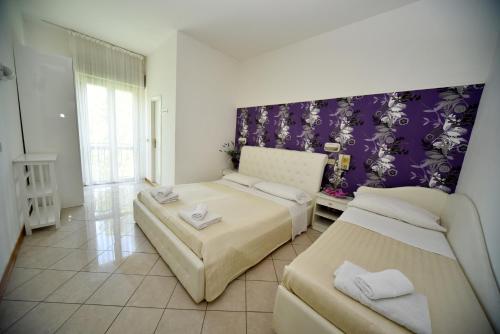 a bedroom with two beds and a purple wall at Hotel Marika in Rimini