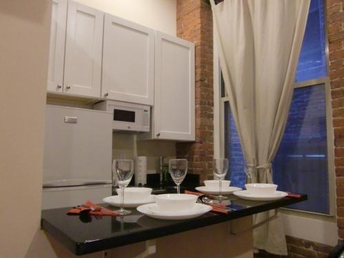 Una cocina con gabinetes blancos y una mesa con copas de vino. en Studios Midtown Manhattan, en Nueva York