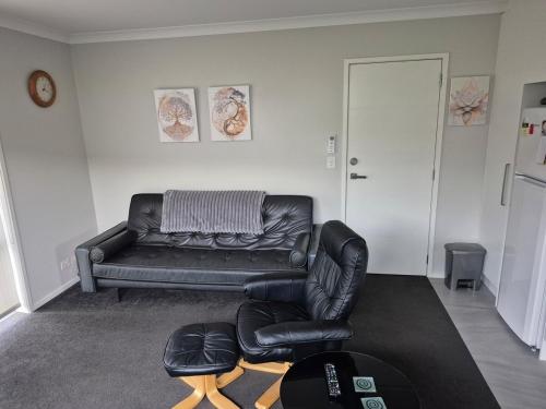 a living room with a leather couch and a chair at Affordable Luxury One Bedroom Apartment in Pukekohe in Pukekohe East