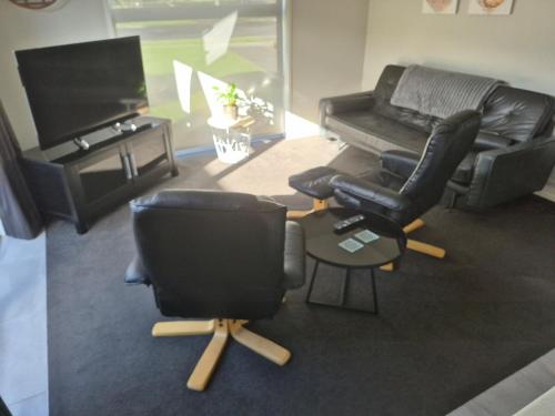 a living room with two chairs and a television at Affordable Luxury One Bedroom Apartment in Pukekohe in Pukekohe East