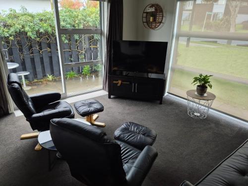 a living room with black leather furniture and a flat screen tv at Affordable Luxury One Bedroom Apartment in Pukekohe in Pukekohe East