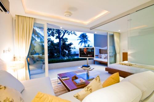 a living room with a white couch and a tv at Code Samui Hotel in Mae Nam